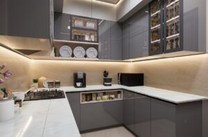 Sleek and modern kitchen with grey cabinets and marble countertops, featuring lighting.